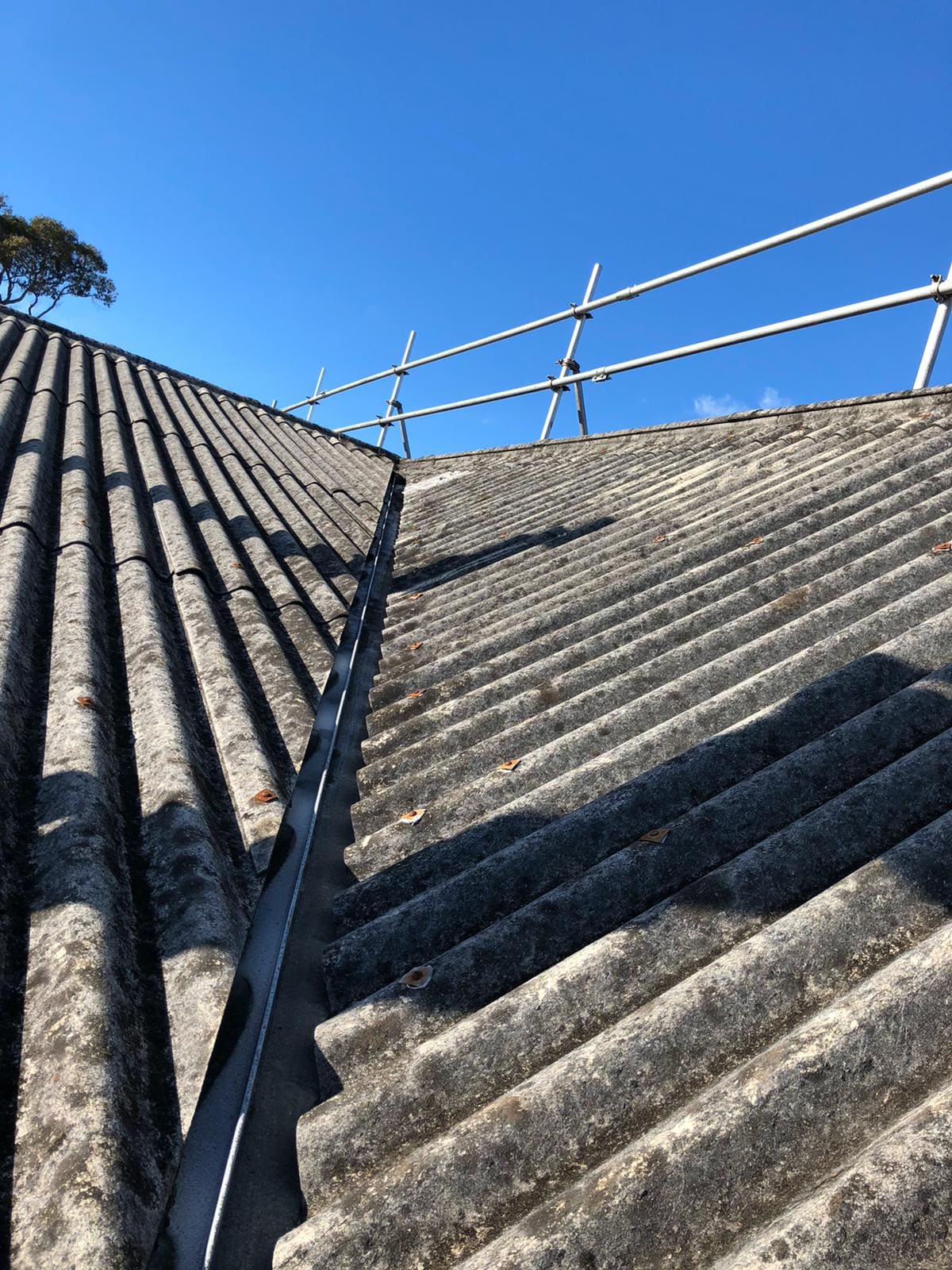 Asbestos roof valley before removal, with edge protection installed