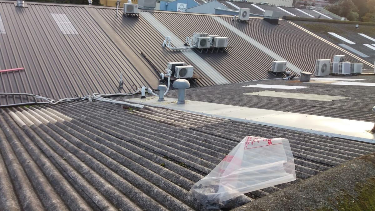 Staged asbestos re-roof showing old asbestos sheets beside new roofing