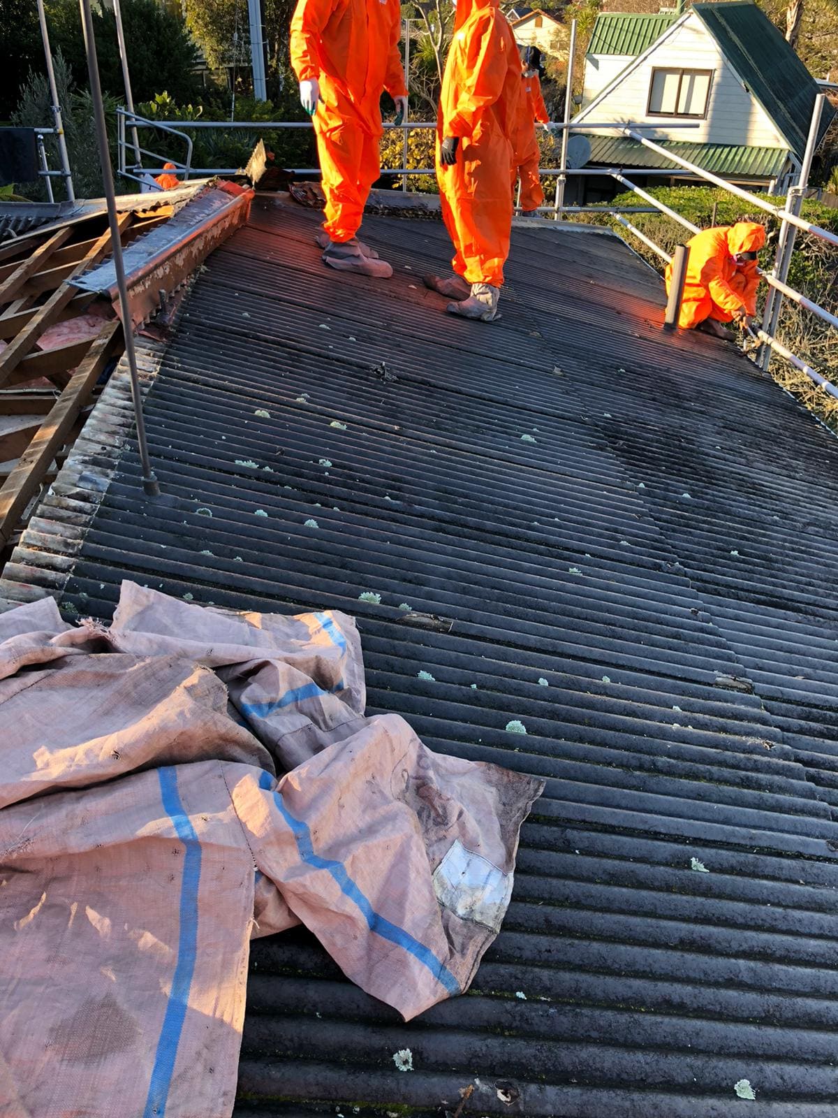 Crew in full PPE wrapping asbestos roofing on site