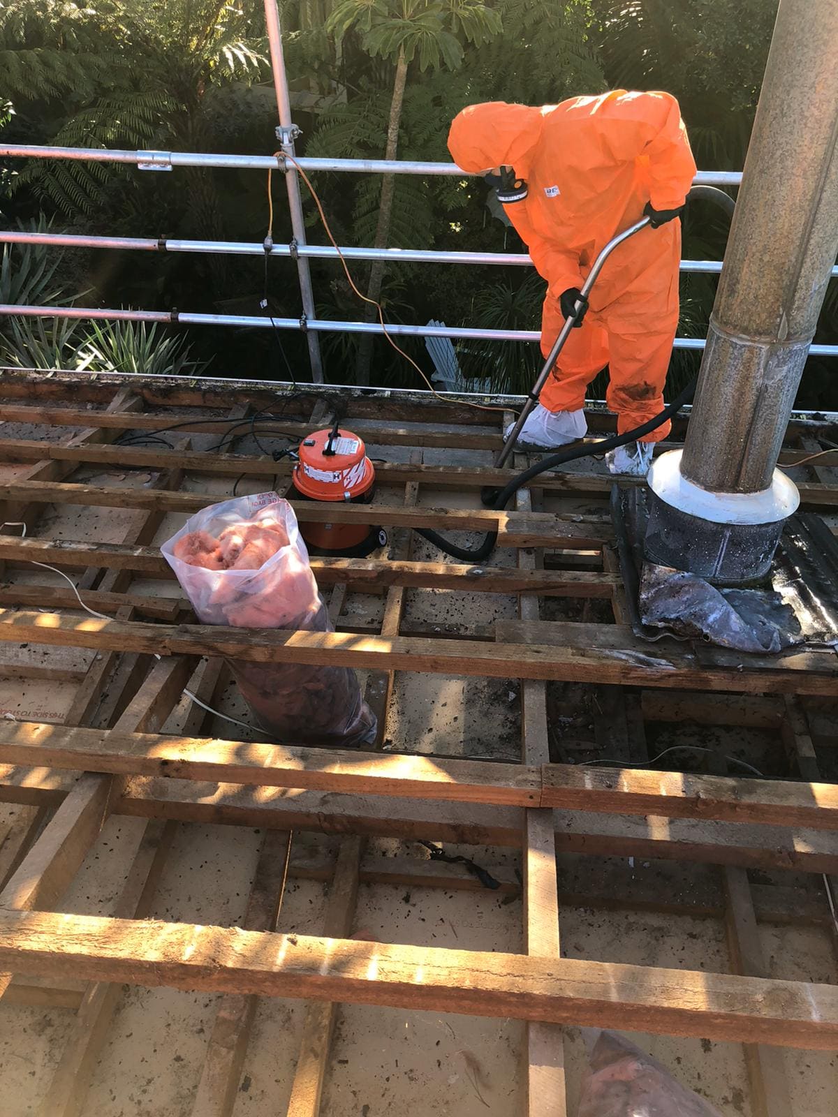 JP Franklin crew member in full protective equipment clearing an asbestos roof